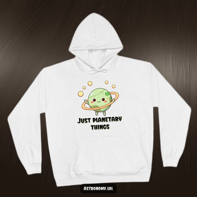 Funny planet hoodie featuring a happy celestial body juggling small moons within its glowing rings, comfortable and amusing.