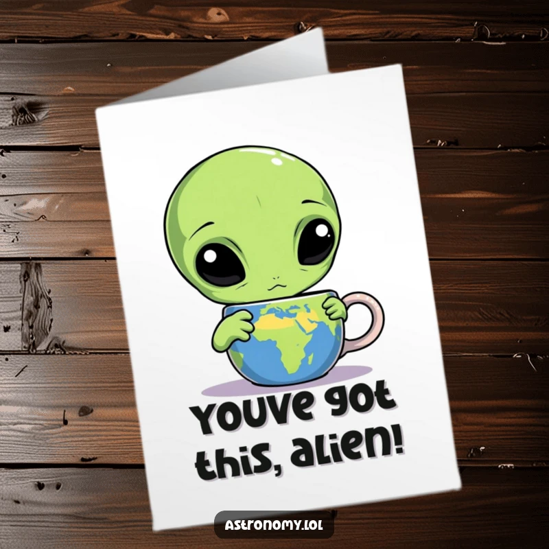 Funny Free Printable Congrats Card: A confused alien with three eyes examines an Earth mug with curiosity.